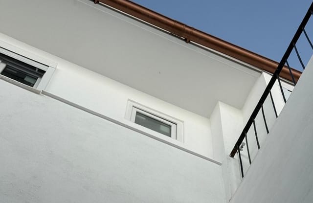 Fachada rehabilitada de Calle San Pablo, Jerez de la Frontera: enfoscado blanco nuevo, carpintería y canalón de cobre